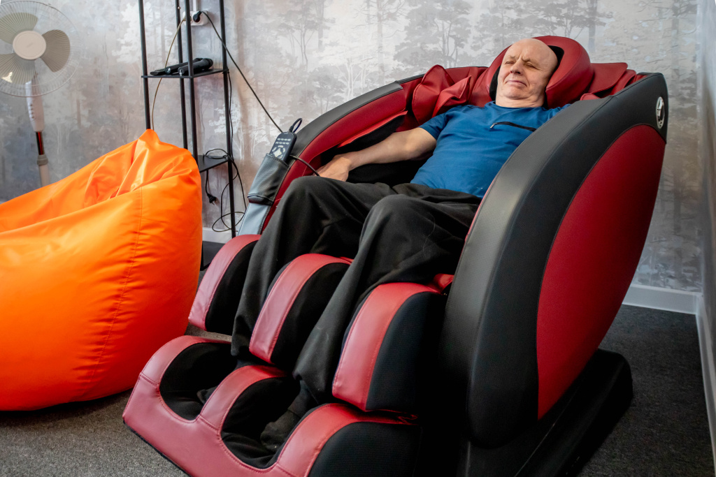 пожилой мужчина сидит на массажном кресле пожилой мужчина сидит на массажном кресле